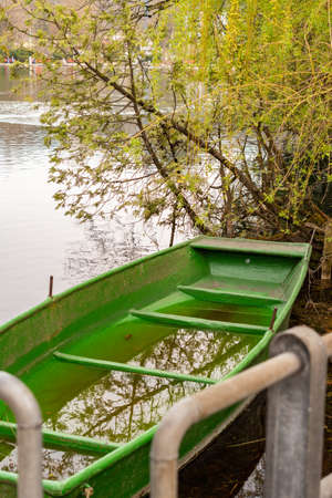 Werdenberg, Switzerland, March 29, 2022 Small green boat is filled with water and is drifting at the bay in a lakeの写真素材