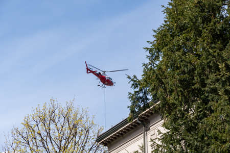 Chur, Switzerland, April 11, 2022 Helicopter is doing some cargo transportation work overhead the city center on a sunny dayのeditorial素材