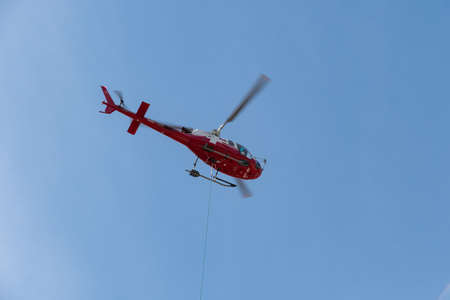 Chur, Switzerland, April 11, 2022 Helicopter is doing some cargo transportation work overhead the...