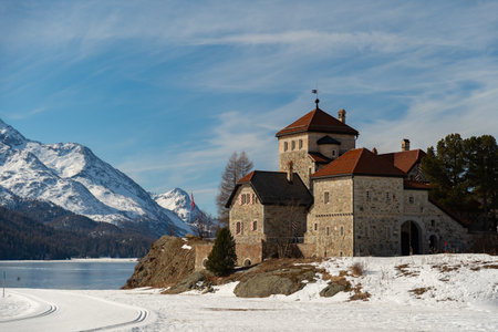 Silvaplana, Switzerland, February 21, 2023 Historic old castle Crap da Sass at the lake of Silvaplana surrounded by an incredible winter panorama on a sunny dayのeditorial素材