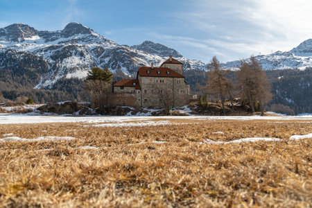 Silvaplana, Switzerland, February 21, 2023 Historic old castle Crap da Sass at the lake of Silvaplana surrounded by an incredible winter panorama on a sunny dayのeditorial素材