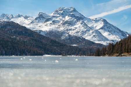 Silvaplana, Switzerland, February 21, 2023 Incredible winter panorama with a view over the frozen lake of Silvaplana and the snow covered summit of the mount Corvatsch in the backgroundの写真素材