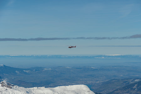 Jungfraujoch, Canton Bern, Switzerland, February 11, 2023 Helicopter is flying along the snow covered mountains on a sunny dayのeditorial素材