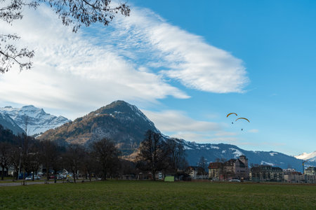 Interlaken, Switzerland, February 11, 2023 Parachute is landing on a green field in the city centerのeditorial素材