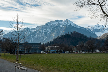 Interlaken, Switzerland, February 11, 2023 View over a green park with the snow covered alps in the backgroundのeditorial素材