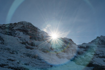 Sun is rising behind a summit of the snow covered alps