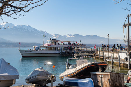 Oberhofen, Canton Bern, Switzerland, February 12, 2023 Small boat is taking tourists to a trip over the lake of Thun on a sunny dayのeditorial素材
