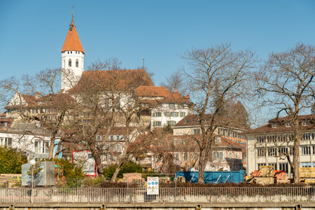 Thun, Switzerland, February 13, 2023 Waterfront at the Aare river in the city center with the historic city church on a hill in the backgroundのeditorial素材