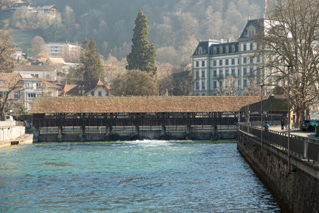 Thun, Switzerland, February 13, 2023 Historic old wooden bridge across the Aare river at the water...