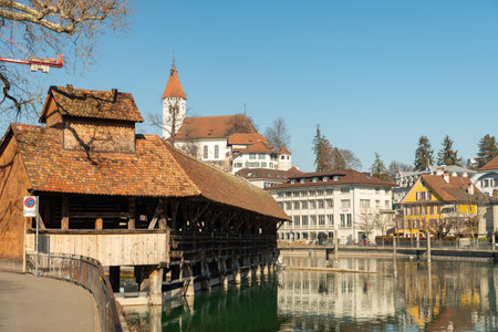 Thun, Switzerland, February 13, 2023 Historic old wooden bridge across the Aare river at the water...