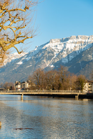Interlaken, Switzerland, February 10, 2023 Water promenade along the Aare river in the city center with the majestic alps in the backgroundの写真素材