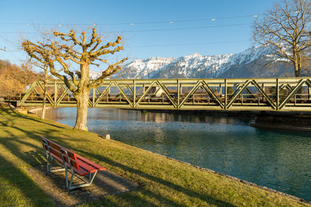 Interlaken, Switzerland, February 10, 2023 Water promenade along the Aare river in the city center with the majestic alps in the backgroundの写真素材