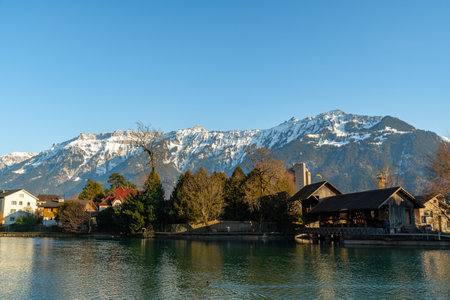 Interlaken, Switzerland, February 10, 2023 Water promenade along the Aare river in the city center with the majestic alps in the backgroundのeditorial素材