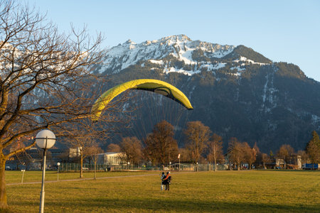 Interlaken, Switzerland, February 10, 2023 Parachute is landing on a green field in the city centerのeditorial素材