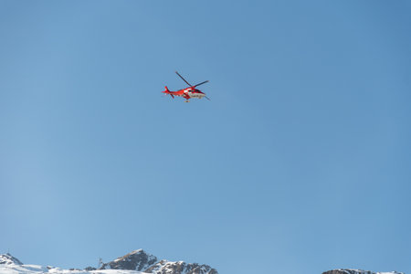 Saint Moritz, Switzerland, February 21, 2023 REGA air ambulance helicopter in the blue skyのeditorial素材