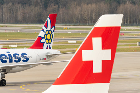 Zurich, Switzerland, January 2, 2023 Edelweiss Air Airbus A320-214 aircraft behind the Swiss logo on the rudder of another planeのeditorial素材