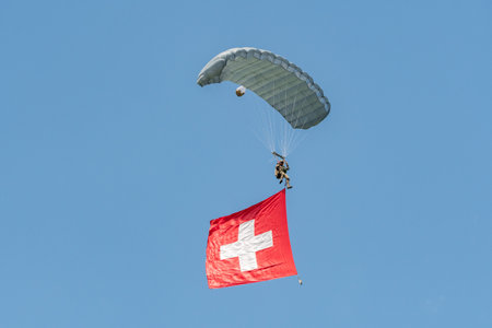 Mollis, Switzerland, August 18, 2023 Swiss Parawings Parachuter with a waving swiss flag during an air displayのeditorial素材