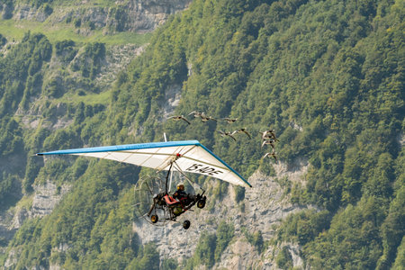 Mollis, Switzerland, August 18, 2023 Ultralight airplane is escorted with birds during an air displayのeditorial素材