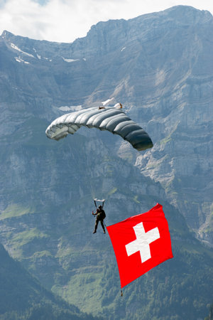 Mollis, Switzerland, August 18, 2023 Swiss Parawings Parachuter with a waving swiss flag during an air displayのeditorial素材
