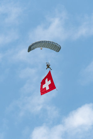 Mollis, Switzerland, August 18, 2023 Swiss Parawings Parachuter with a waving swiss flag during an air displayのeditorial素材