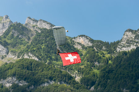 Mollis, Switzerland, August 18, 2023 Swiss Parawings Parachuter with a waving swiss flag during an air displayのeditorial素材
