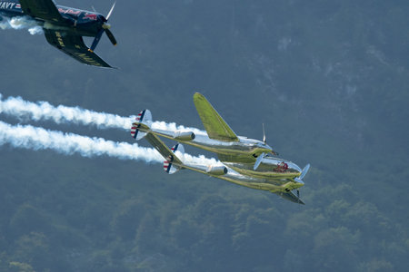 Mollis, Switzerland, August 18, 2023 Lockheed P-38L Lightning and a Chance Vought F4U-4 Corsair historic aircraft in formation flight during an air displayのeditorial素材