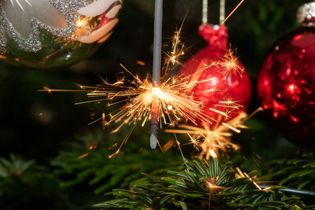 Ruggell, Liechtenstein, December 24, 2022 Burning bengal fire during christmas celebration on a fir...