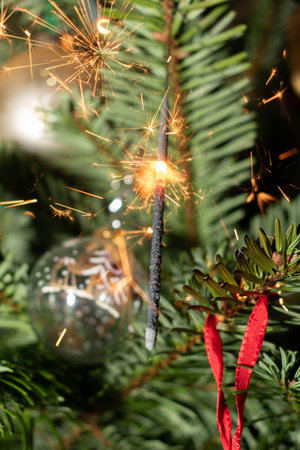 Ruggell, Liechtenstein, December 24, 2022 Burning bengal fire during christmas celebration on a fir...