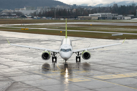 Zurich, Switzerland, January 17, 2024 YL-AAR Air Baltic Bombardier CS-300 or Airbus A220-300 aircraft is taxiing along the apron during a rain showerのeditorial素材
