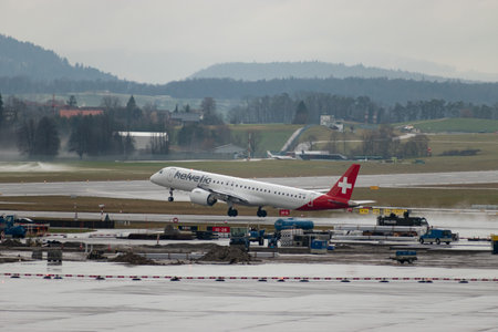 Zurich, Switzerland, January 17, 2024 HB-AZK Helvetic Airways Embraer E195-E2 aircraft is taking off from runway 28 during a rain showerのeditorial素材