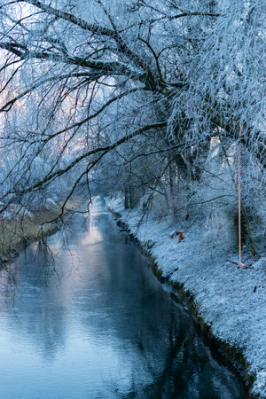 Vaduz, Liechtenstein, December 31, 2024 Small river flows along a frozen landscape on a cold dayの写真素材