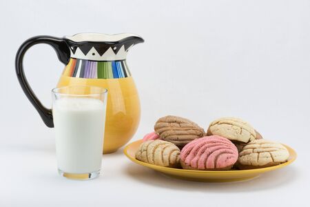 Pitcher and glass of milk next to plate of concha breadの写真素材