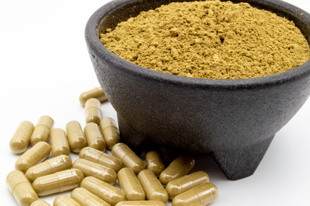Maeng Da Kratom powder in black bowl with capsules of Kratom along side.の写真素材