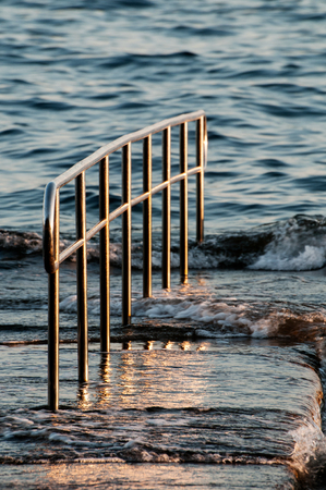 Pier fence and wavy sea at sunsetの写真素材