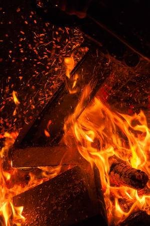 Closeup of chainsaw cutting burning wood and logs, night shot