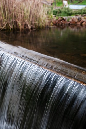 Closeup of silvery water pouring over threshold in a fresh streamの写真素材