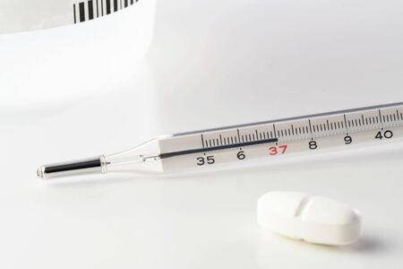 Medical mercury thermometer and white pill isolated on white background. Vaccination, flu, medicine,...