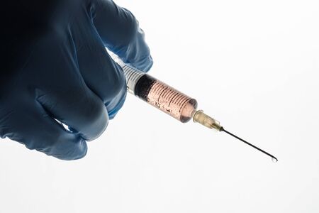 Right hand in a blue latex glove holding syringe with vaccine isolated on white background....