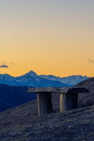 Vacant wooden bench on the hilltop with nice scenic view of Alps in the evening. Travel, hiking,...