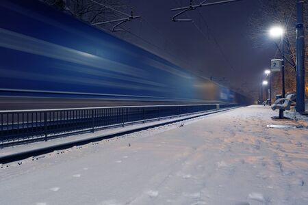 Passing freight train in blurred motion at train station on a winter night. Transportation and...