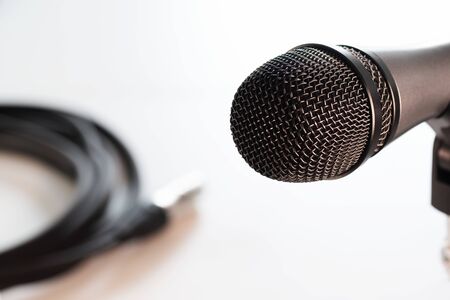 Vocal microphone head with black grille and balanced cable with xlr connector in background isolated on white. Music, audio, hi-fi, karaoke and sound reproduction.の写真素材