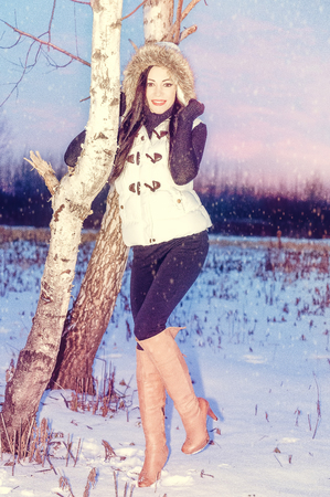Snowing winter portrait of young woman brunette, close tree , pink lips , cathy brown eyes smilesの写真素材