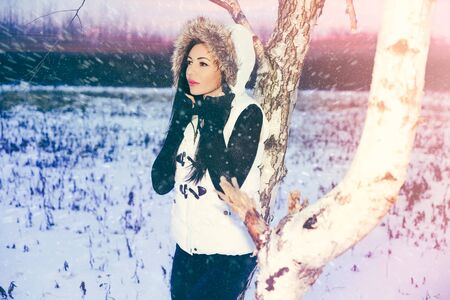 blizzard winter portrait of young woman brunette, close tree , pink lips , cathy brown eyesの写真素材