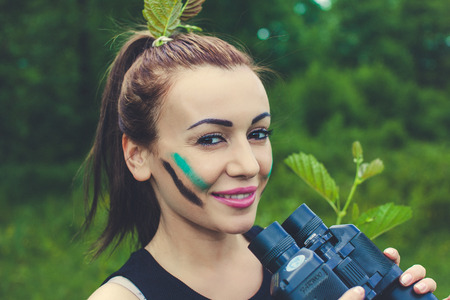 Pretty  woman hunter smiling Camo Face Paint bicular in hand