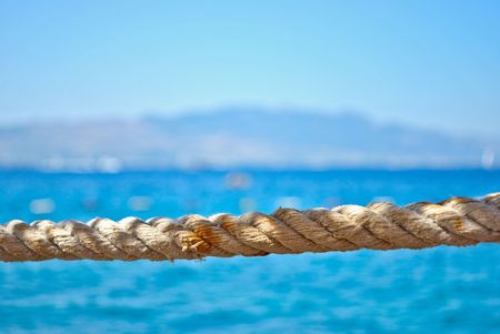 Old rope streched in front of blue, calm seawater in the summerの写真素材