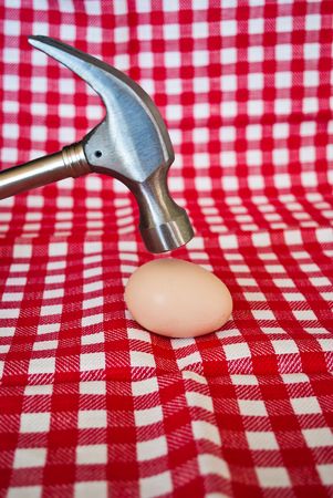 Steel hammer breaking a chicken egg on a striped red backgroundの写真素材