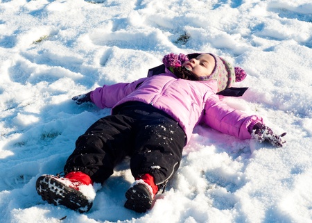 Small girl with winter clothes playing in the snowの写真素材
