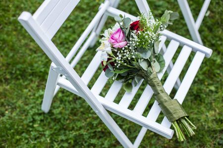 beautiful bouquet of flowers on a white chair on a background of grass.の写真素材