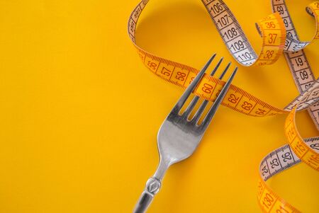 fork with a yellow meter that measures body volume. empty city for inscription. concept of healthy...