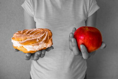 girl holds a pen in one hand and a red apple in the other. diet. The girl is black and white and the products are colored. Healthy Eating . The right choice. Lots of calories. Vitamins in fruits. Her gluttony.の写真素材